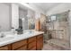 Bathroom with double sinks, shower, and wood cabinets at 18208 W Skyline Dr, Surprise, AZ 85374