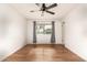 Well-lit bedroom with wood-look floors, ceiling fan and window with curtains at 10343 W Prairie Hills Cir, Sun City, AZ 85351