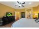 Spacious main bedroom with a large TV and ceiling fan at 15938 W Summerwalk Dr, Surprise, AZ 85374