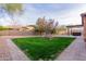 Landscaped backyard with grassy area, paved pathway, and covered patio at 30213 N 124Th Ln, Peoria, AZ 85383