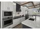 Modern kitchen featuring stainless steel appliances, white cabinets, a sleek black range hood, and marble countertops at 3322 N Valencia Ln, Phoenix, AZ 85018