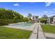 A backyard with a swimming pool, lush greenery, and stone walkways leading to an outdoor seating area at 3322 N Valencia Ln, Phoenix, AZ 85018
