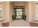 Stylish front entrance with a black framed glass door, potted plants, and a decorative welcome mat at 9655 N 130Th St, Scottsdale, AZ 85259
