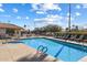 Outdoor pool area with lounge chairs, tables, umbrellas, and a jacuzzi under a bright blue sky with fluffy clouds at 10626 E Voax Dr, Sun Lakes, AZ 85248