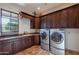 Laundry room with washer, dryer and dark wood cabinets at 10712 E Greythorn Dr, Scottsdale, AZ 85262