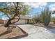 View of the driveway showcasing mature desert landscaping and a two-car garage, enhancing the curb appeal of this lovely home at 1801 E Aire Libre Ave, Phoenix, AZ 85022