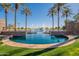 Sparkling community pool with palm trees and lake view at 43808 W Wade Dr, Maricopa, AZ 85138