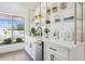 Bright butler's pantry features white cabinets, white countertop, gold accents and convenient drink fridge at 9031 N 83Rd Way, Scottsdale, AZ 85258