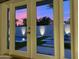 View of a backyard pool and patio through french doors at sunset at 9448 N 80Th Pl, Scottsdale, AZ 85258