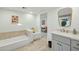 Clean bathroom with a bathtub, double vanity, and view of living room at 9448 N 80Th Pl, Scottsdale, AZ 85258