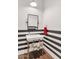 Stylish bathroom with black and white striped walls, pedestal sink, and modern mirror at 5989 E Sapphire Ln, Paradise Valley, AZ 85253