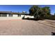 Exterior shot showcasing backyard featuring desert landscaping and mature shade tree, with a view of the home's exterior at 6449 E Dodge St, Mesa, AZ 85205