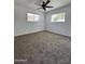 Spacious bedroom with plush carpet, two windows, and ceiling fan at 6449 E Dodge St, Mesa, AZ 85205