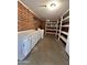 Organized laundry room with storage shelves, white cabinets and a brick accent wall at 6449 E Dodge St, Mesa, AZ 85205