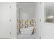 Bathroom with a white standalone tub and shower featuring colorful geometric tiling, bright lighting, and a floral patterned floor at 6811 N 11Th Ave, Phoenix, AZ 85013