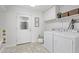 Bright laundry room featuring a washer, dryer, overhead cabinets, art prints, and backyard access at 6811 N 11Th Ave, Phoenix, AZ 85013