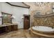Luxurious bathroom featuring a stone surround tub, decorative chandelier, and stone flooring at 6876 S Star Dr, Gilbert, AZ 85298