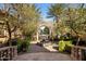 Courtyard entrance with mature trees, fountain and pavers leading to a stone archway at 6876 S Star Dr, Gilbert, AZ 85298
