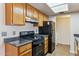 Galley kitchen with wood cabinets, granite counters, and black appliances at 14645 N Fountain Hills Blvd # 217, Fountain Hills, AZ 85268