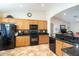 Kitchen with wood cabinets, granite countertops, black appliances, and tile flooring at 16549 W Desert Ln, Surprise, AZ 85388