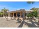 Covered patio and backyard with gravel and palm trees at 16935 W Villagio Dr, Surprise, AZ 85387