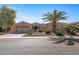 Tan stucco house with palm trees and gravel driveway at 16935 W Villagio Dr, Surprise, AZ 85387