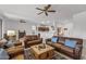 Open living room with leather seating, a view into the kitchen, and ceiling fans at 16935 W Villagio Dr, Surprise, AZ 85387