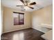 Bedroom with dark laminate flooring, ceiling fan, and built-in desk at 23618 W Adams St, Buckeye, AZ 85396