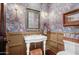 Elegant powder room with floral wallpaper, white pedestal sink, and wicker accents at 27931 N Montana Dr, Rio Verde, AZ 85263