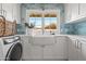 Bright laundry room with white cabinetry, farmhouse sink, stylish backsplash, and modern washer at 5314 E Calle Del Norte --, Phoenix, AZ 85018