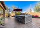 Brick outdoor kitchen with built-in grill, bar seating, and umbrella at 5902 W Gambit Trl, Phoenix, AZ 85083