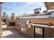 Outdoor kitchen featuring a built-in grill, fireplace, and mini-fridge at 3213 N 41St Pl, Phoenix, AZ 85018