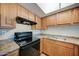 Kitchen with wood cabinets, black appliances, and granite countertops at 3810 N Maryvale Pkwy # 1060, Phoenix, AZ 85031