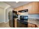 Kitchen with wood cabinets, black appliances, and granite countertops at 3810 N Maryvale Pkwy # 1060, Phoenix, AZ 85031