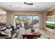 Spacious living room with leather sofas, a stone fireplace, and sliding glass doors leading to the pool at 41711 N Maidstone Ct, Anthem, AZ 85086