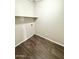 Laundry area with dark wood-look flooring and overhead shelving at 12367 W Woodland Ave, Avondale, AZ 85323