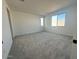 Bright bedroom featuring neutral gray carpet, window views, and white walls at 25318 W Bowker St, Buckeye, AZ 85326