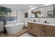 Bathroom boasts a freestanding tub, dual sinks, and a large mirror at 3077 W Ironwood Cir, Chandler, AZ 85226