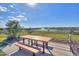 Outdoor wooden picnic table and bench seating near lush landscaping and water features under a clear blue sky at 35350 W Marin Ave, Maricopa, AZ 85138