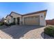 Tan colored house with a brick driveway and two-car garage at 41925 W Arvada Ln, Maricopa, AZ 85138