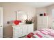 Bright bedroom features white dresser, mirror, and red and white bedding at 14950 W Mountain View Blvd # 3209, Surprise, AZ 85374