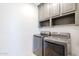 Laundry room with gray cabinets and washer/dryer at 18381 N 93Rd St, Scottsdale, AZ 85255