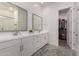 Bright bathroom with double sink vanity, white cabinets, framed mirrors, and walk-in closet at 21754 E Caldwells Ct, Queen Creek, AZ 85142