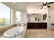 Bright bathroom boasts a luxurious soaking tub, dual sinks, dark cabinets, and a large mirror above the vanity at 5528 E Windstone Trl, Cave Creek, AZ 85331