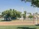 Outdoor sand volleyball court near lake with lush green trees, and clear blue sky at 758 S Lagoon Dr, Gilbert, AZ 85233