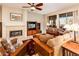 Cozy living room with a fireplace, tiled floors, media center and views of the desert landscape through expansive windows at 18932 N Aztec Point Dr, Surprise, AZ 85387