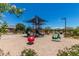 Community playground with slides, shade structures, and various play equipment surrounded by lush landscaping at 20562 E Raven Dr, Queen Creek, AZ 85142