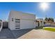 Modern home exterior featuring a clean white facade, artificial turf, and a paver driveway at 2129 S Los Feliz Dr, Tempe, AZ 85282