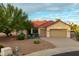 Tan single story house with red tile roof and two car garage in a desert landscape at 22713 N Dusty Trail Blvd, Sun City West, AZ 85375