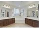 Bright bathroom with a large tub, separate vanities with dark wood cabinets, and natural light from a glass block window at 4615 W Corral Rd, Laveen, AZ 85339